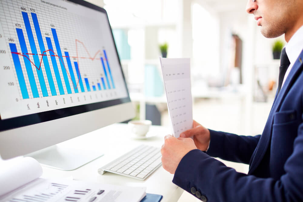 Man in blue suit studying sales chart