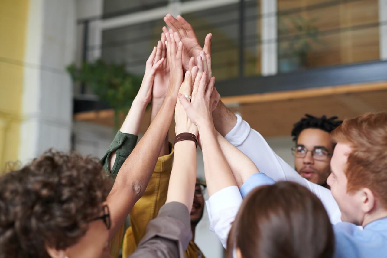 Work colleagues high-fiving themselves in the workplace