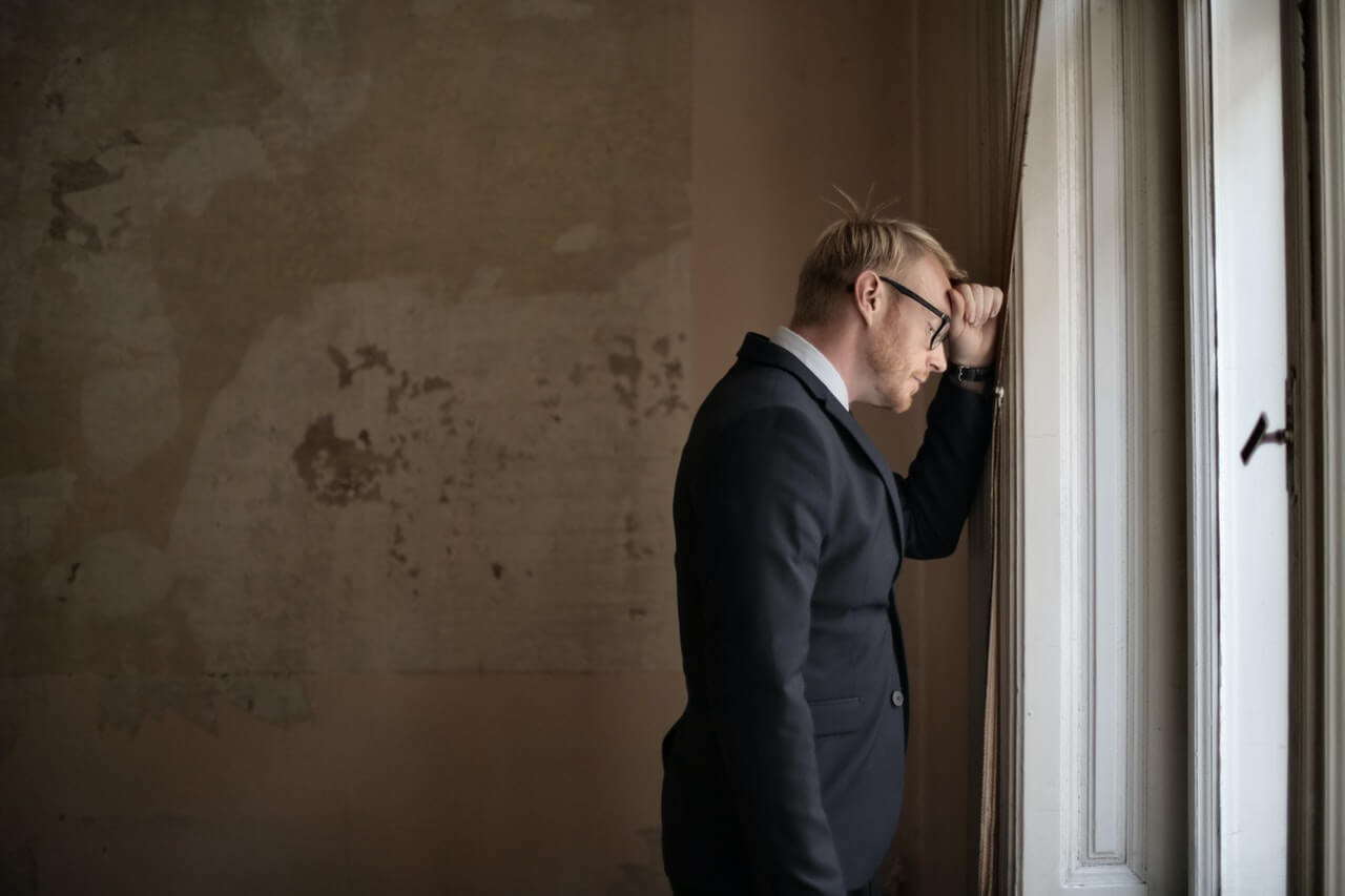 Tired male entrepreneur staring out through the window