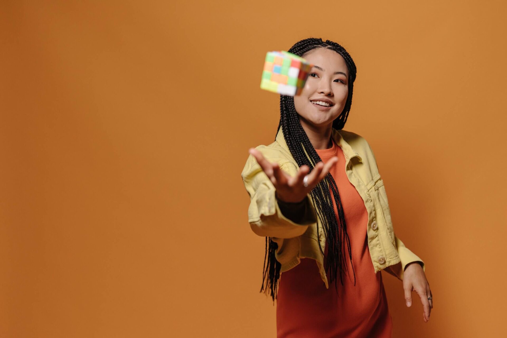 A girl throwing a rubik's puzzle in the air