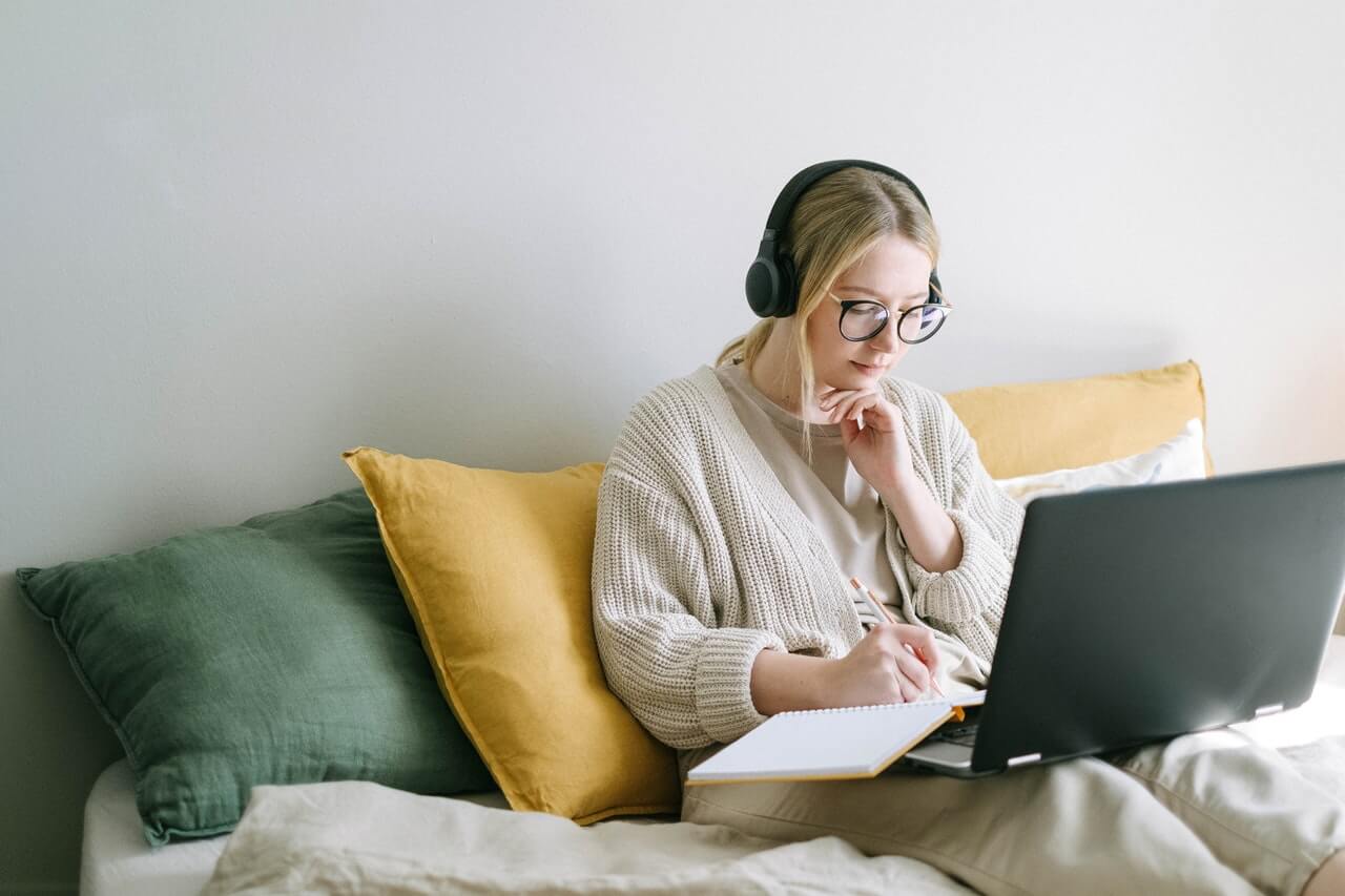 A woman taking notes from an online program