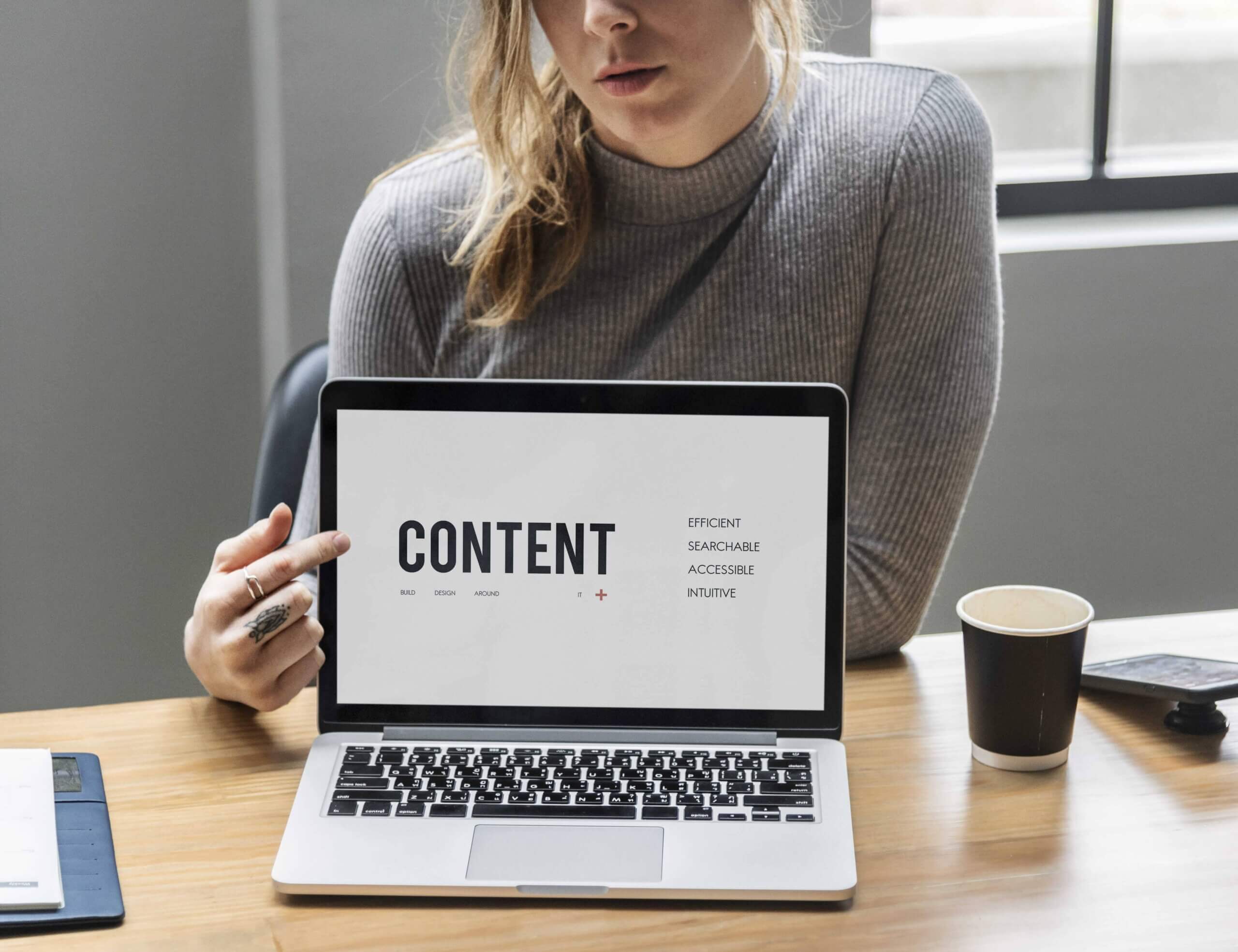 Woman working on a content pointing to a laptop screen