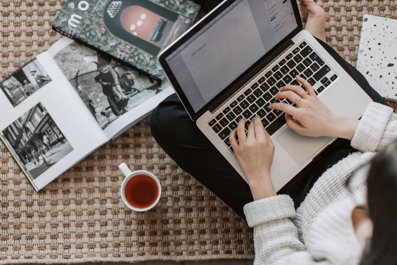 Young person sitting near a mug typing with a laptop