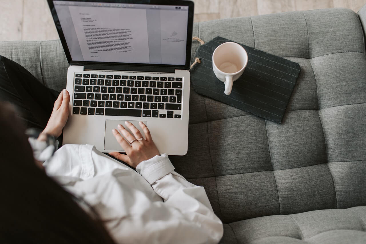 Woman sitting in a couch writing on her laptop