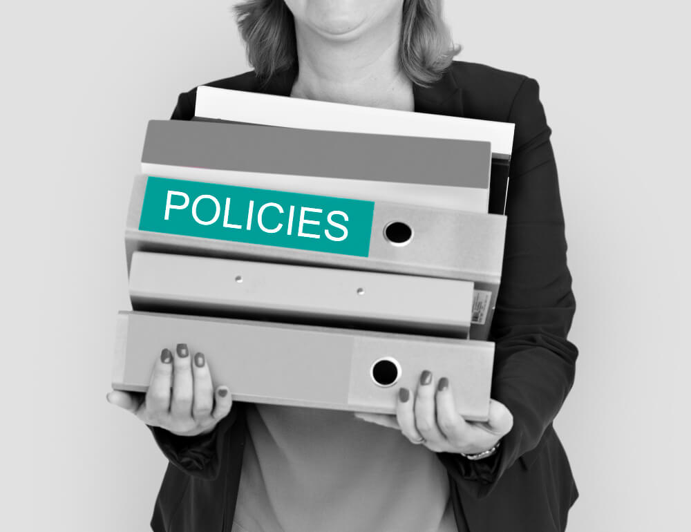 Woman holding a pile of books on business policies and ethics