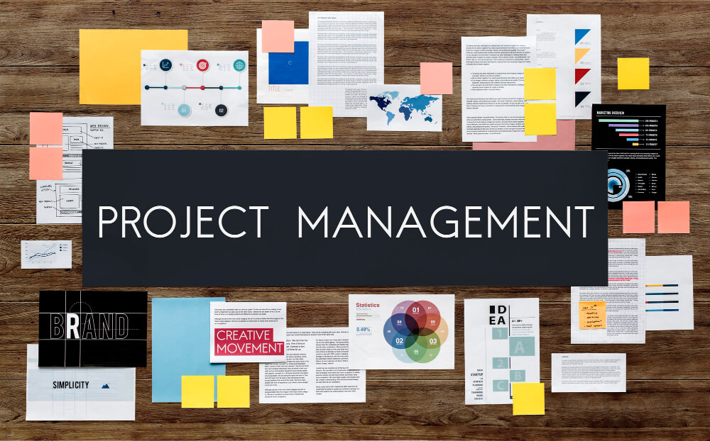 Project management spelt out on a desk full of business concepts