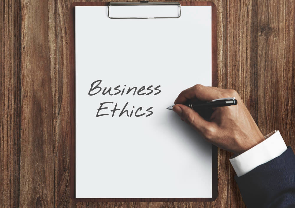 Person writing business ethics on a plain white paper