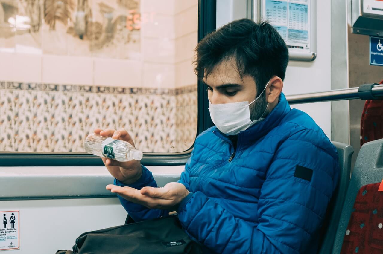 A-man-wearing-a-nose-mask-and-applying-a-hand-sanitizer.