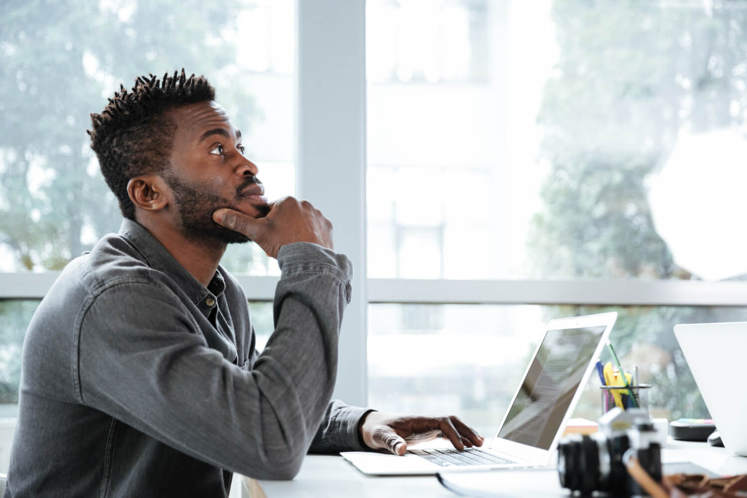 A-man-sitting-and-thinking-while-working-on-his-laptop