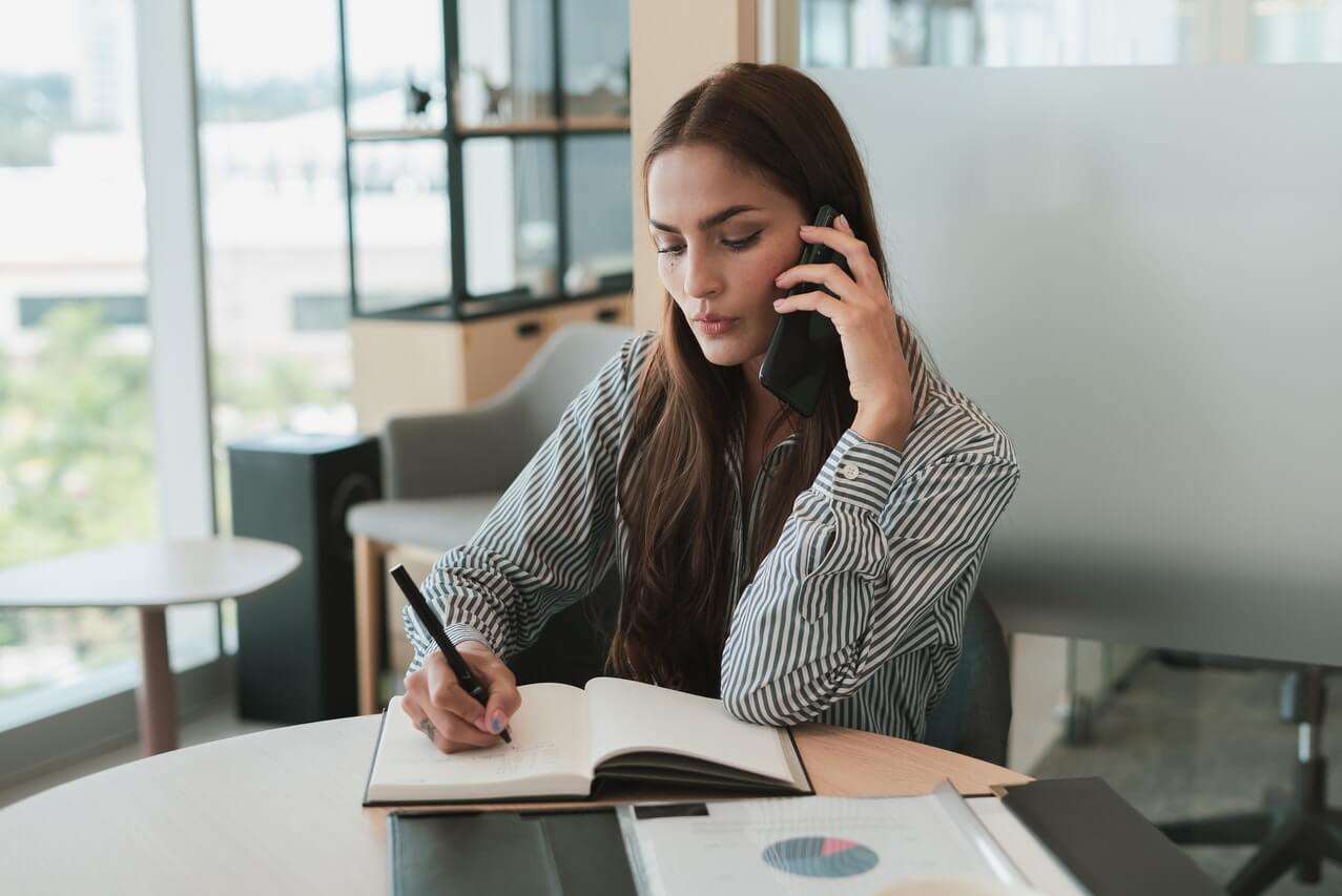 Businesswoman Talking on Phone and Taking Notes