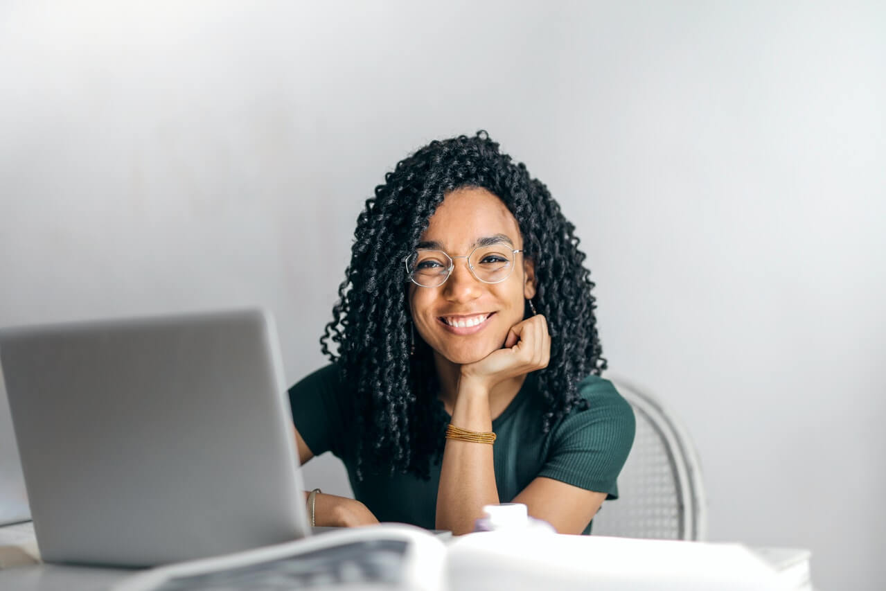 Happy woman sitting at table with laptop