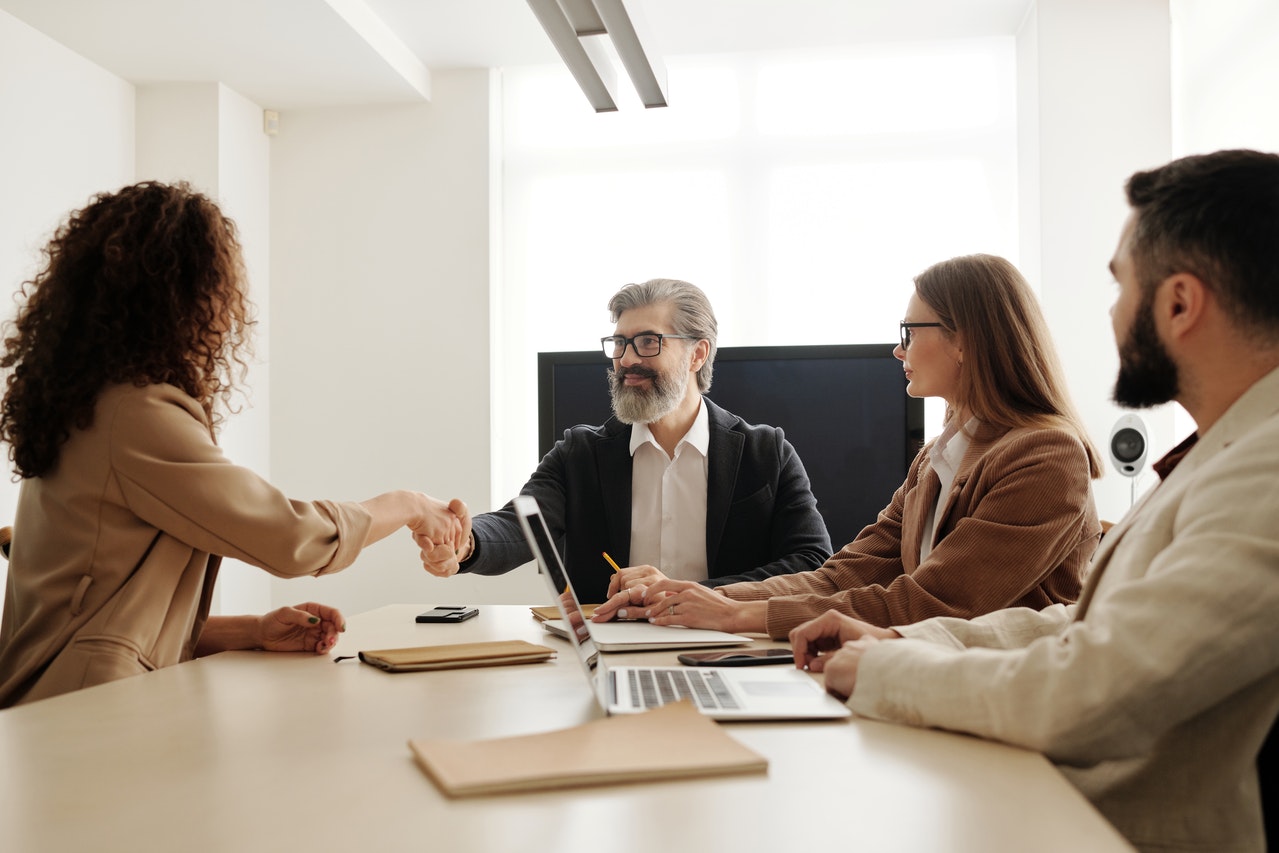 Man in black suit shaking hands with a lady while in a meeting