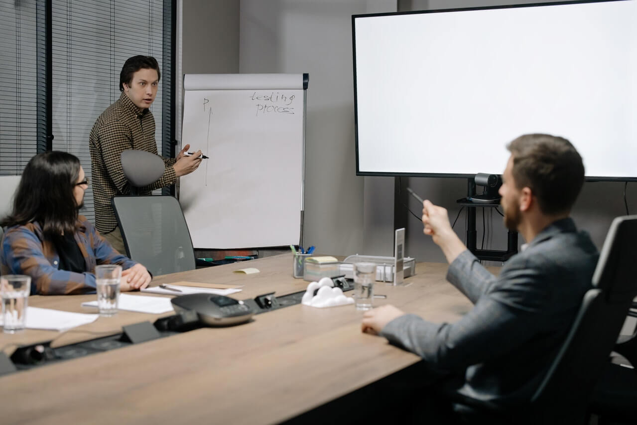 Man presenting at the meeting while writing on a board