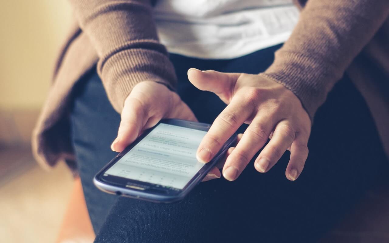 Person Holding Smartphone While Sitting