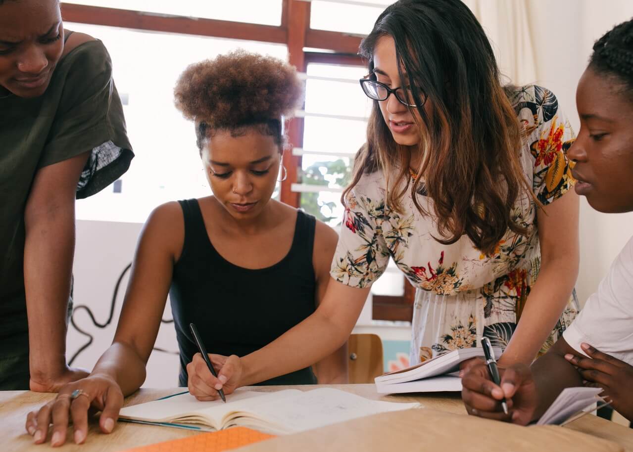 Woman writing on paper while in a meeting