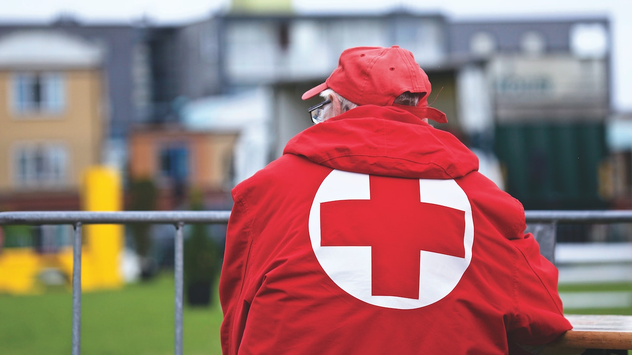 A-red-cross-worker-sitting-and-backing-the-camera-