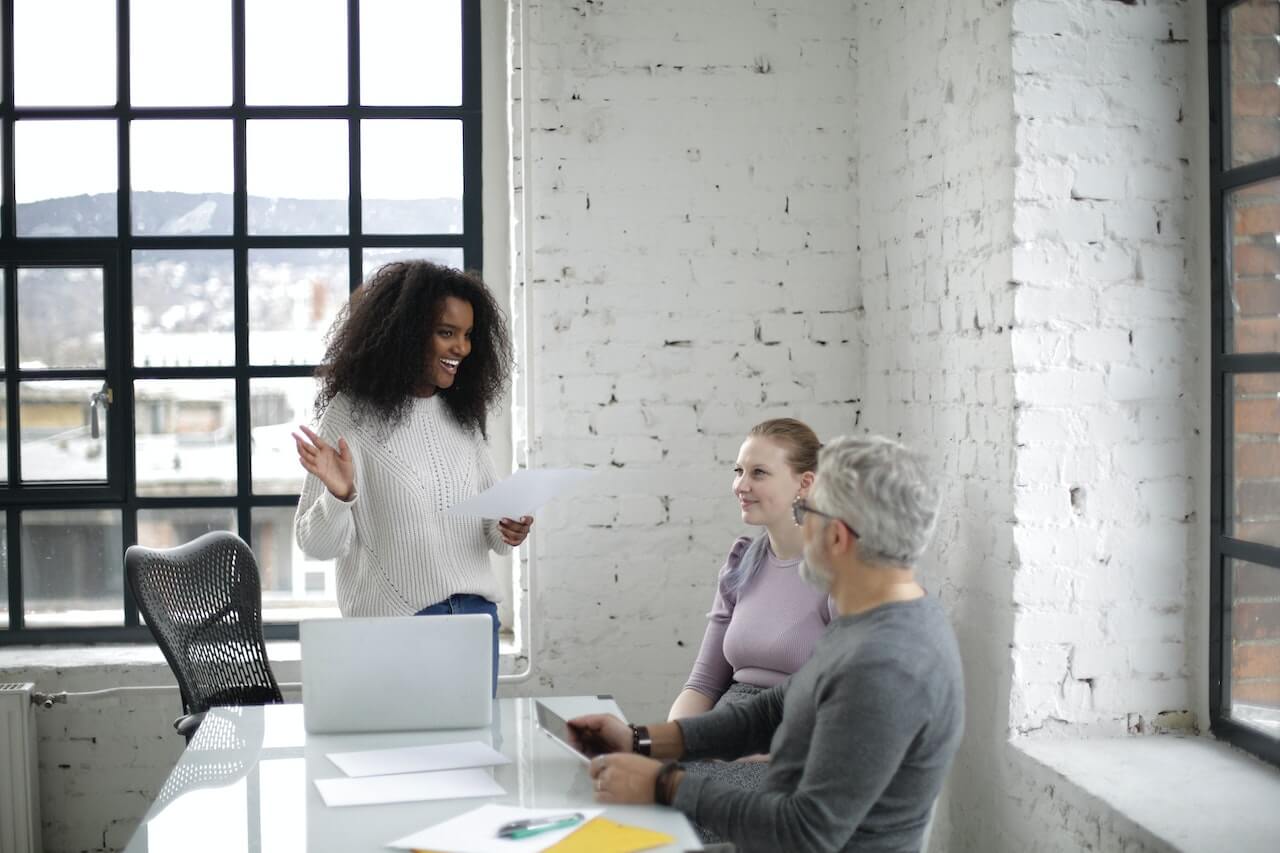 Cheerful colleagues discussing project together in light modern office