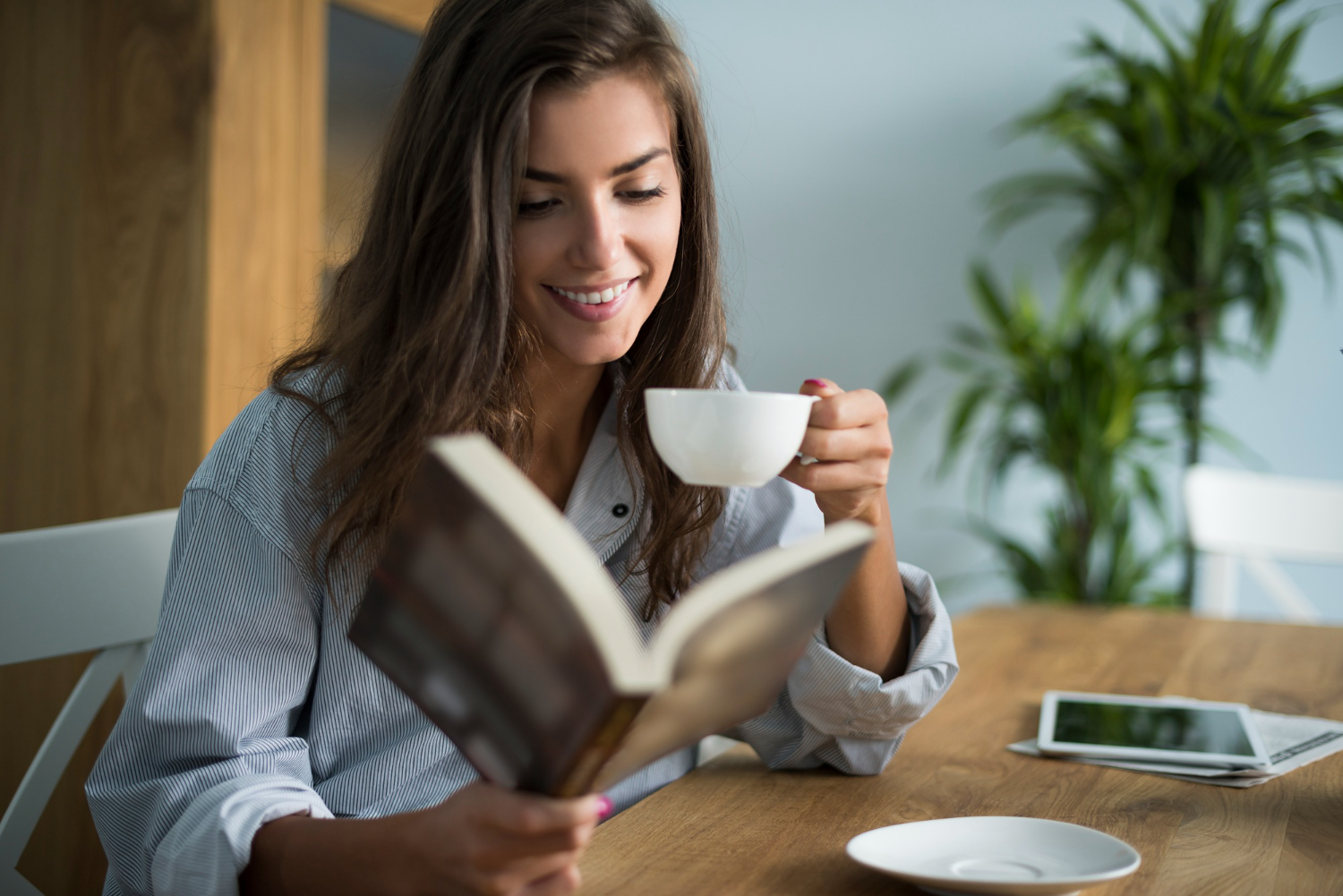 Lady reading a book while holding a cup