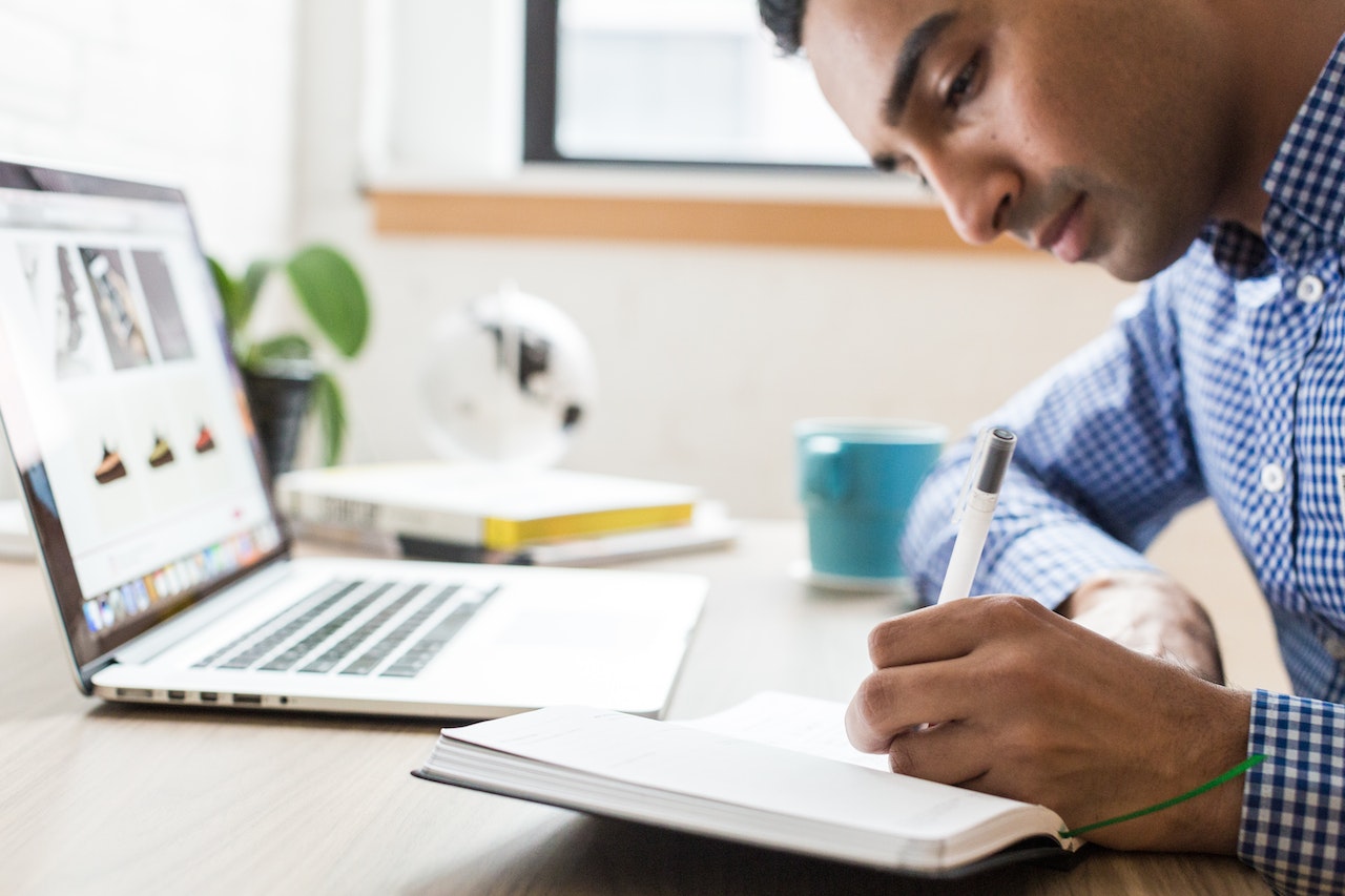 Man Using Ballpoint Pen writing on a note