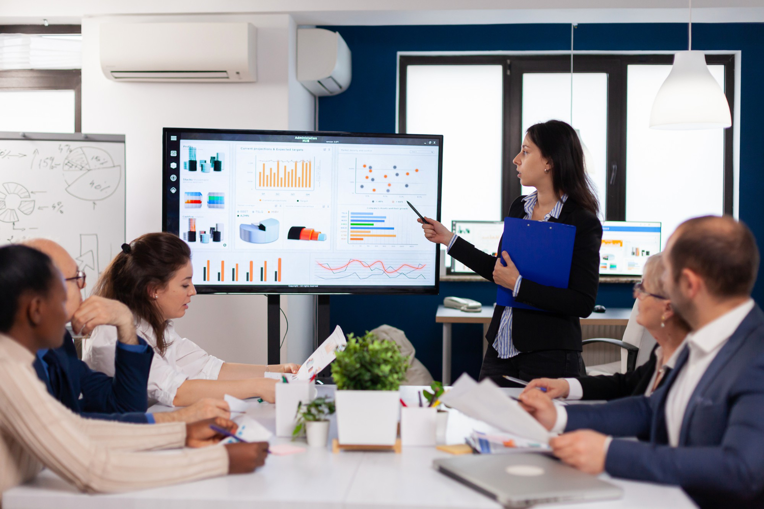 A woman addressing a board of elites in an office