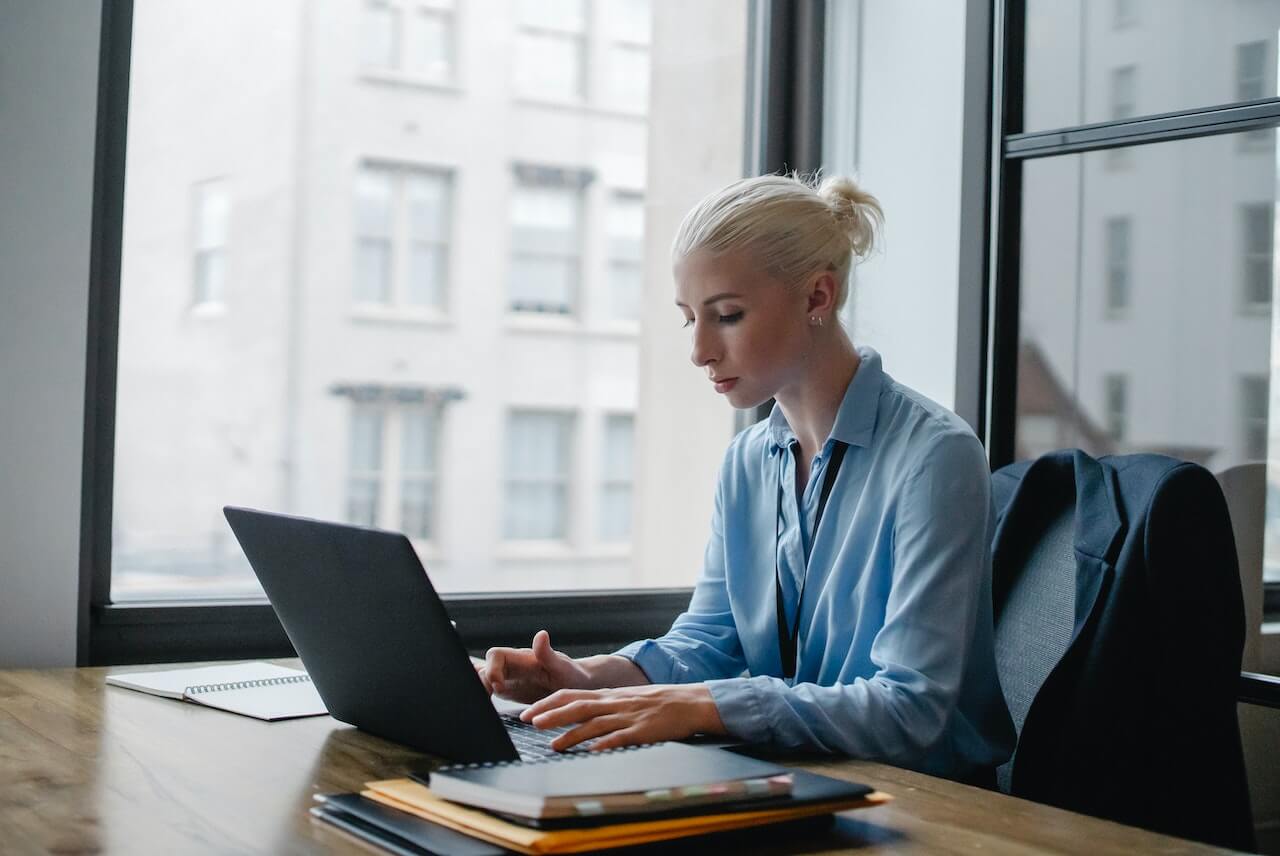 Serious woman typing on laptop in workspace