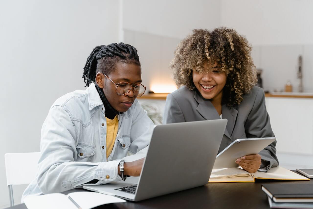 A male and a female colleagues working on their laptop in an office