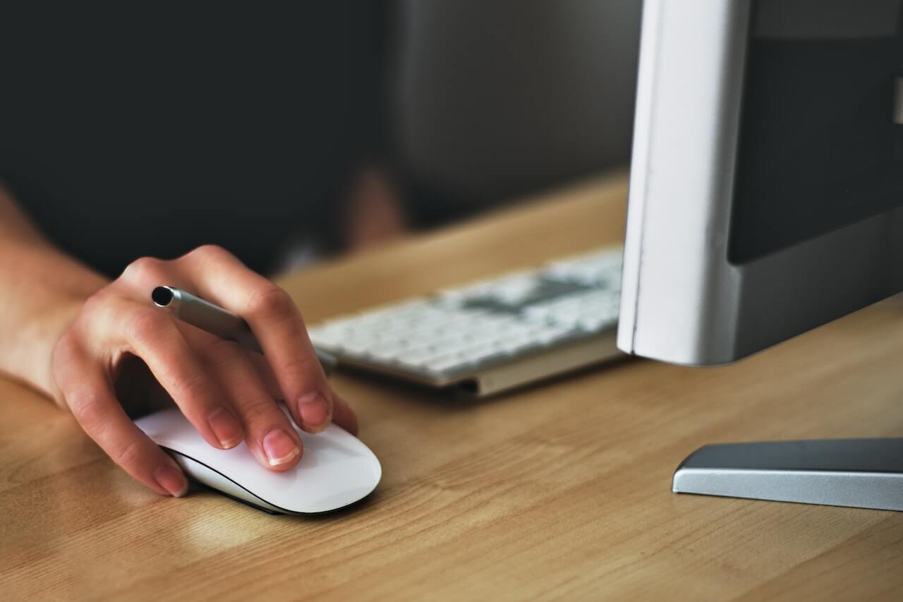 A person holding a mouse on a desk