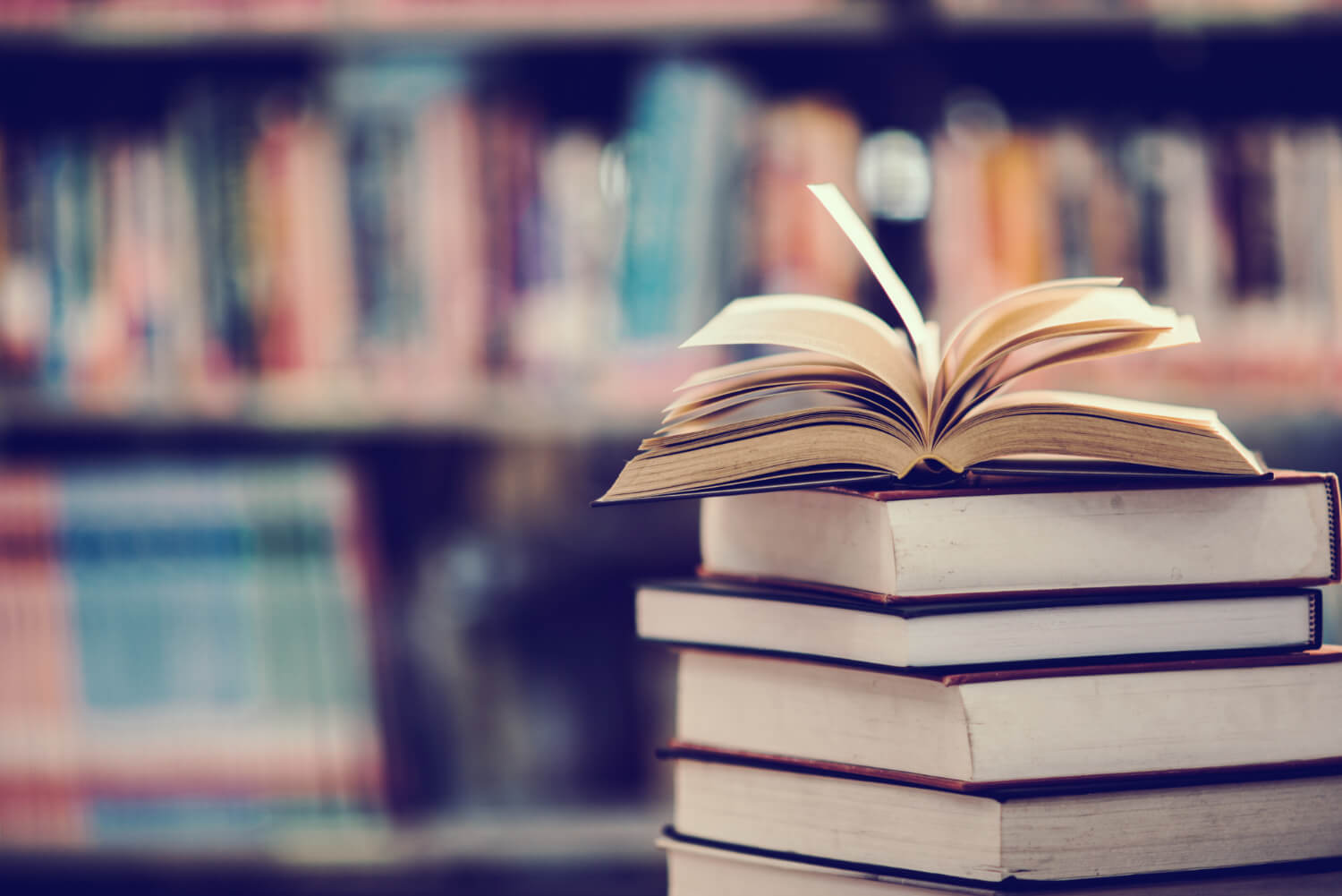 A-pile-of-books-stackeed-up-on-a-table-with-one-opened.