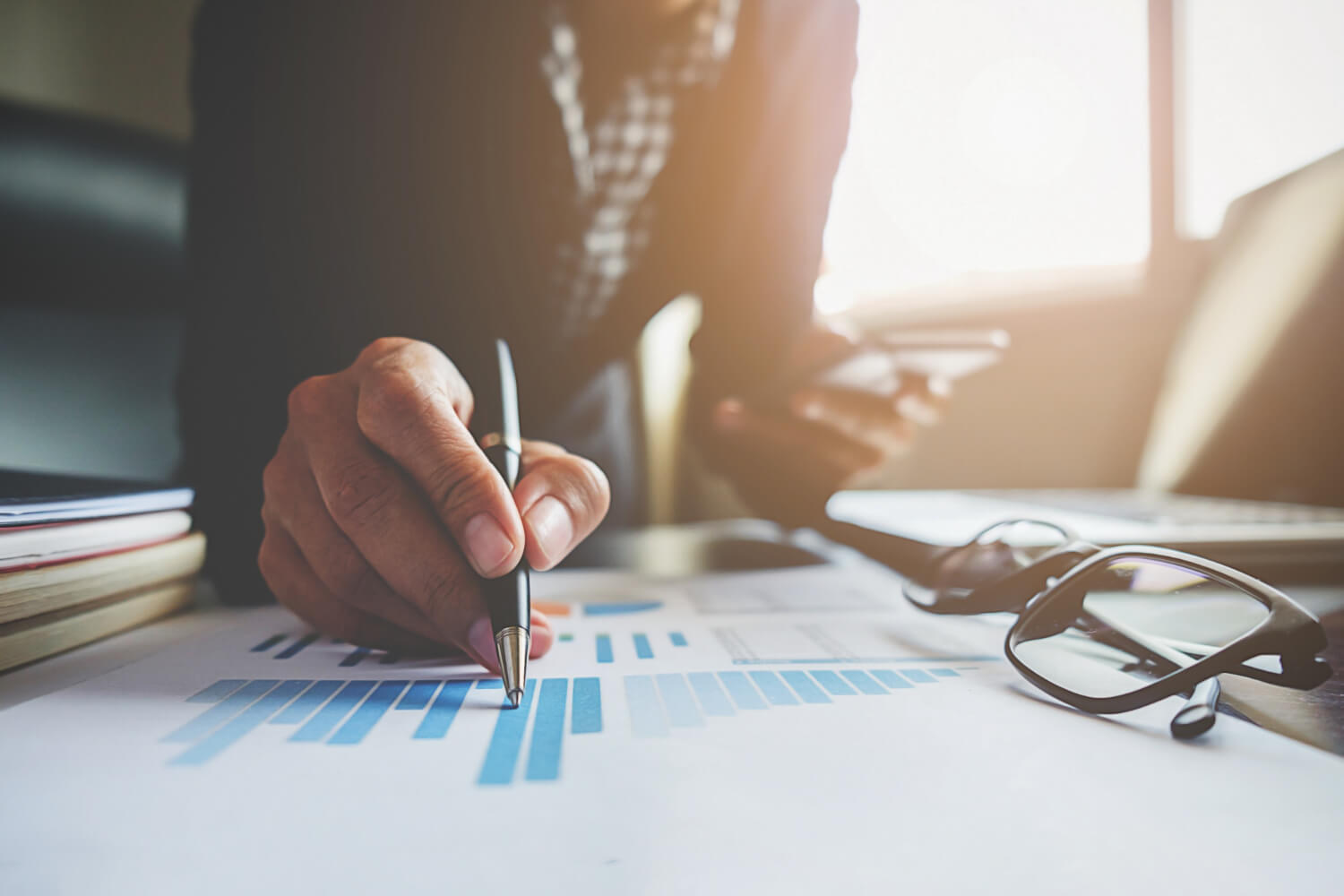 Business person working on a graph while holding a phone