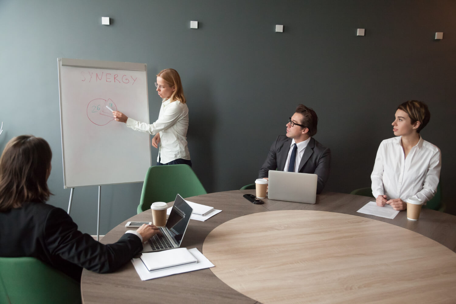 Businesswoman-giving-presention-in a corporate-team-meeting-in an-office