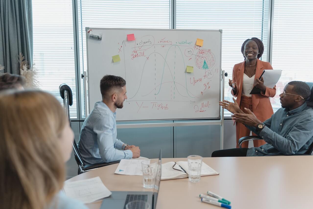 Lady standing close to a while board in a meeting