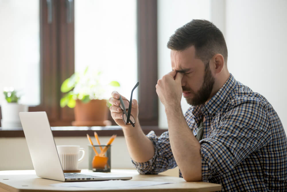 Stressed male massaging nose bridge suffering from headache during a crisis management