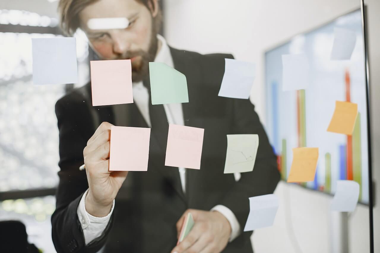 Man Writing on Notes Posted on Glass Wall