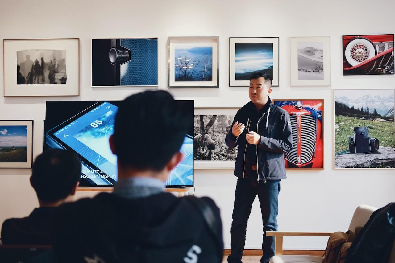 Man beside flat Screen addressing his audience