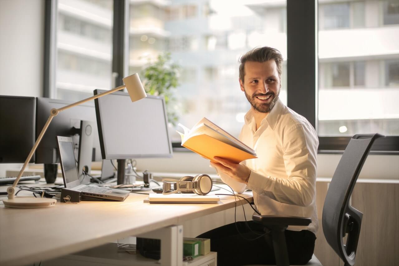 Man holding a book while in his office