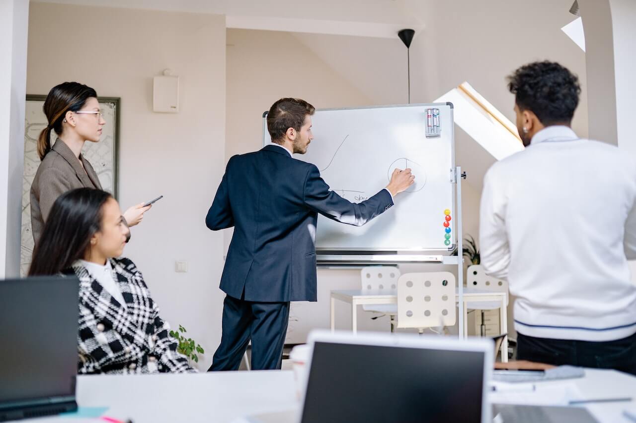 People at the office facing white Board in a meeting