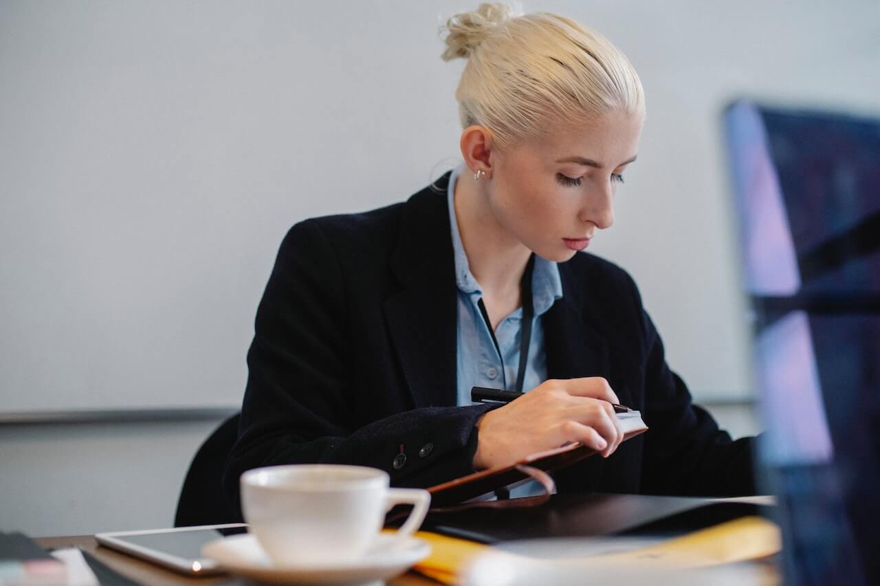 Serious young businesswoman working with report in office