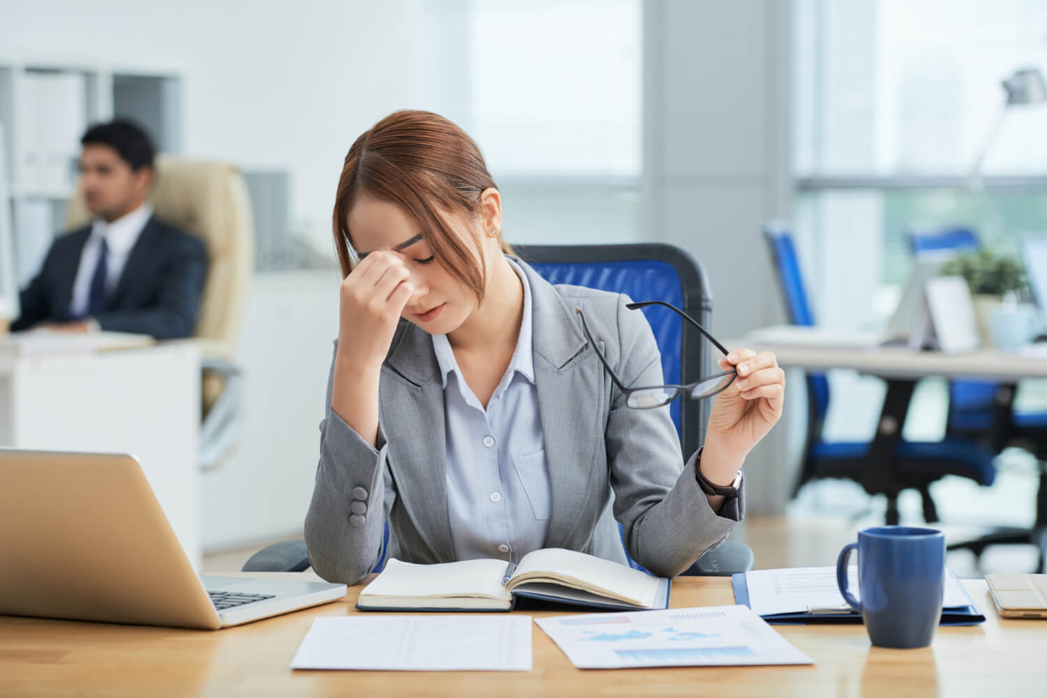 Tired woman-sitting at a desk-office-rubbing-nose