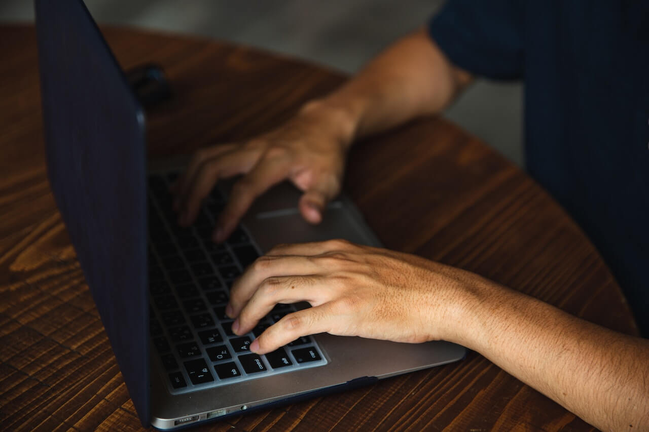 unrecognizable man typing on laptop