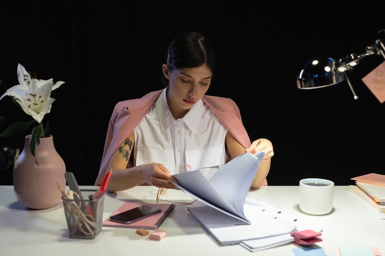 Woman Sitting in Front of a Desk Reading Documents