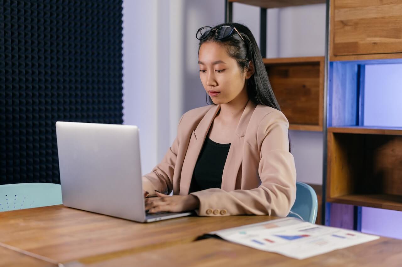 Woman in a Beige Blazer Working on Her Laptop