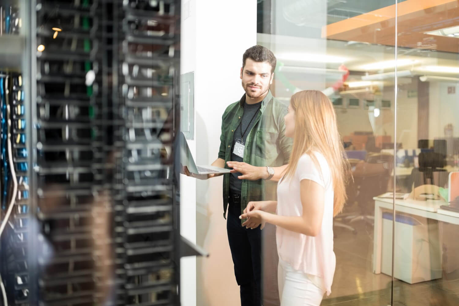 two-business-people-standing-server-room-with-laptop-discussing.