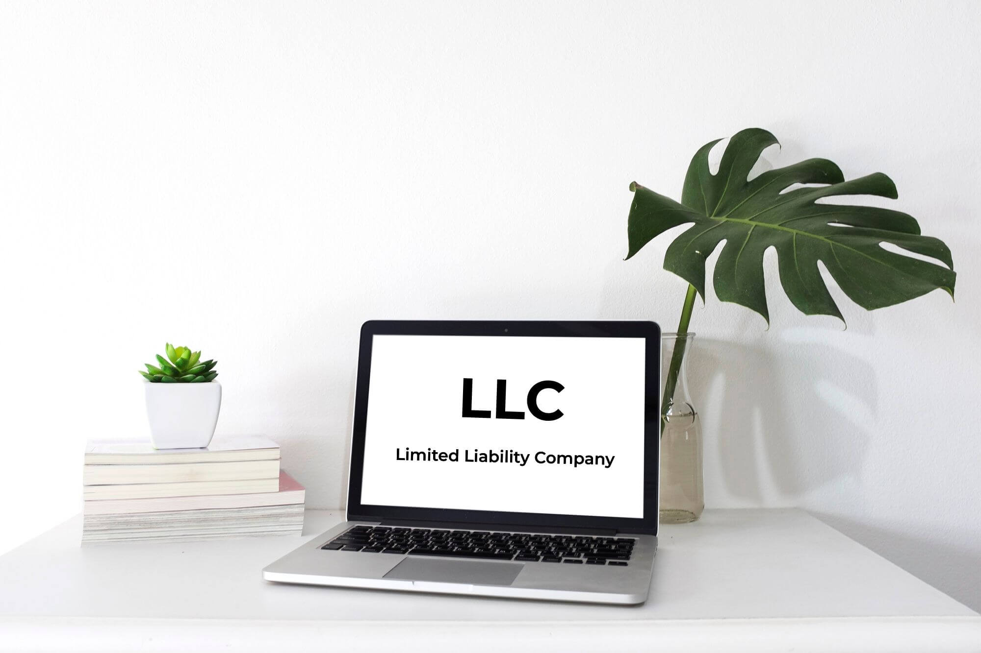 An office laptop on a desk space displaying the words "llc limited liability company" on the screen