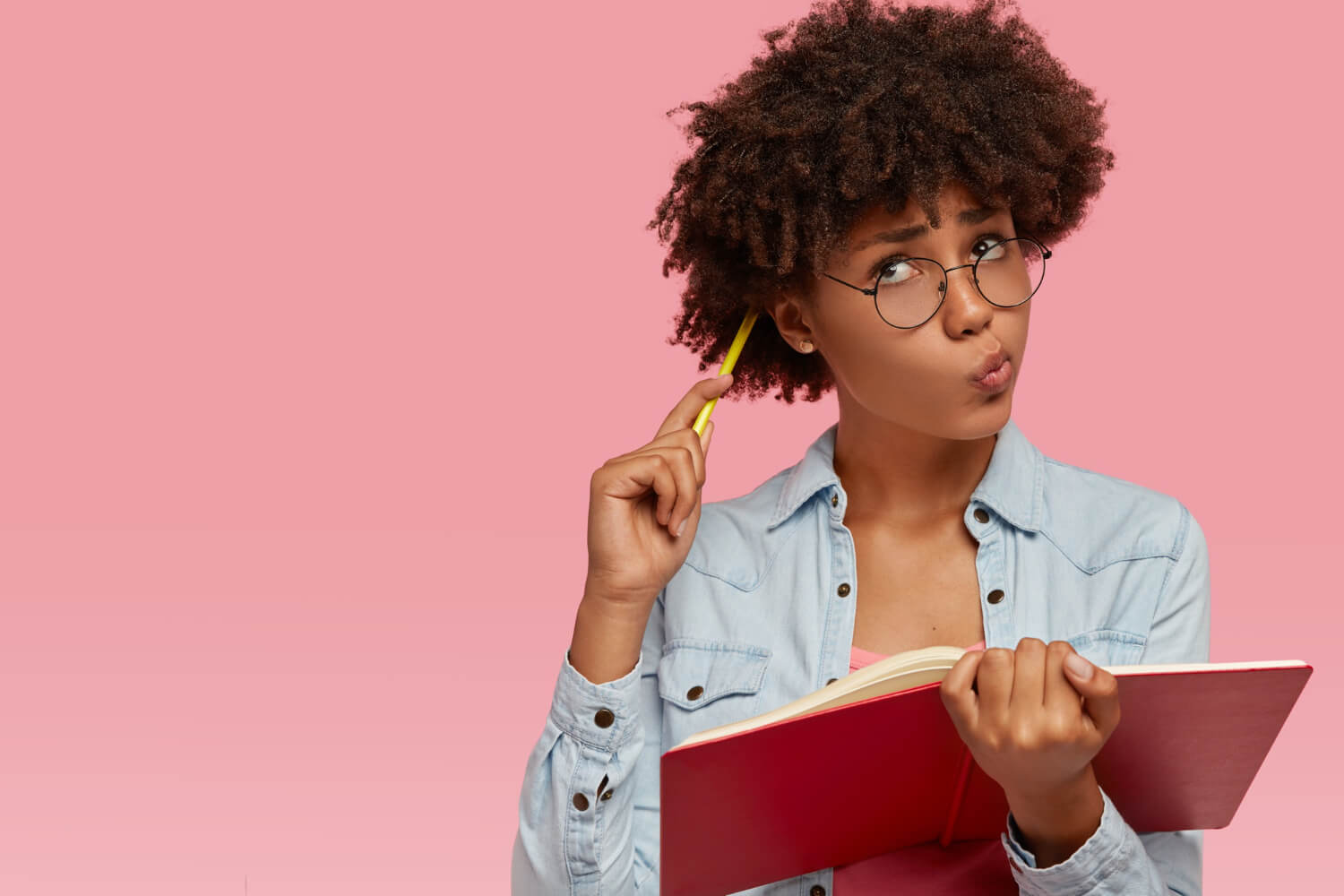 Dark skinned woman scratching her head with a pencil while thinking of a business name