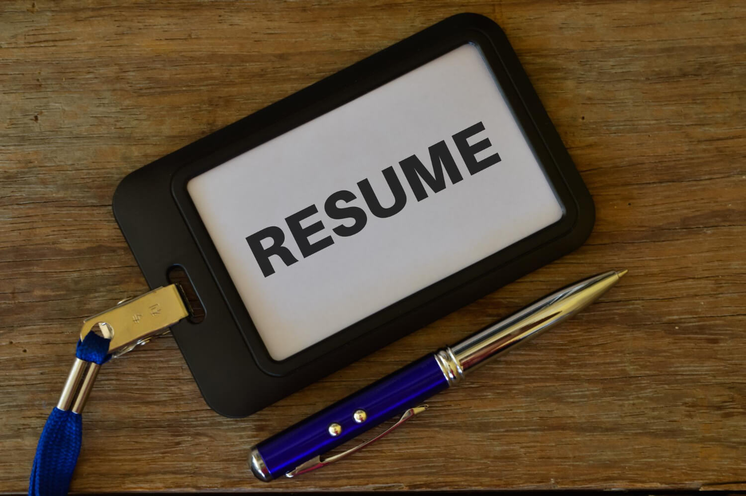 Pen and name tag written with resume over wooden background