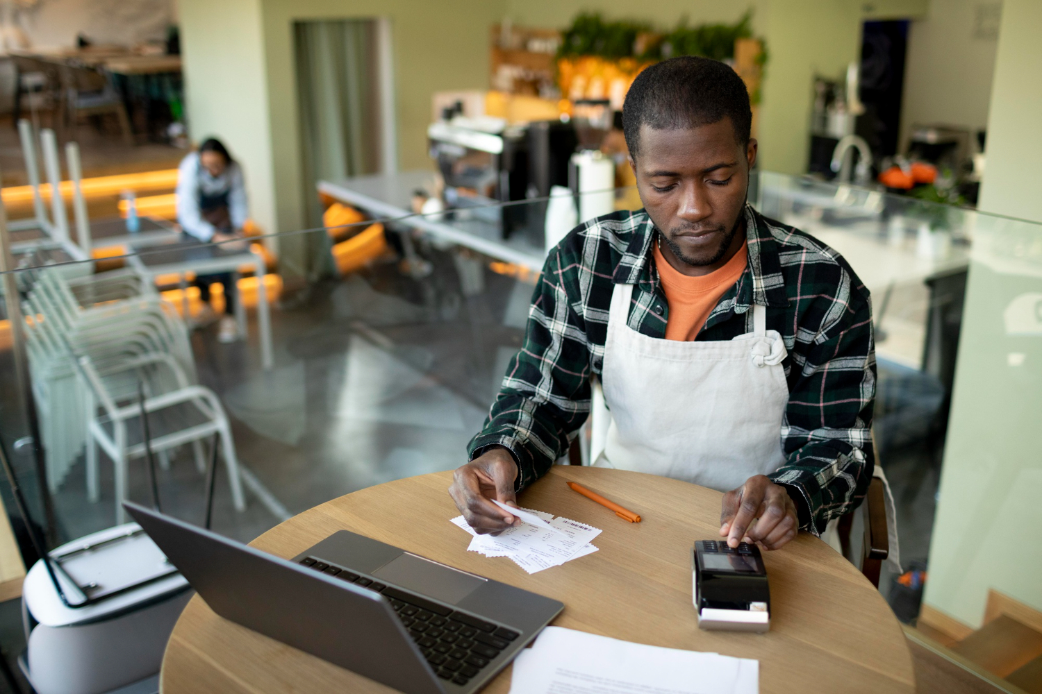 Small business owner in his shop checking receipts with a POS machine