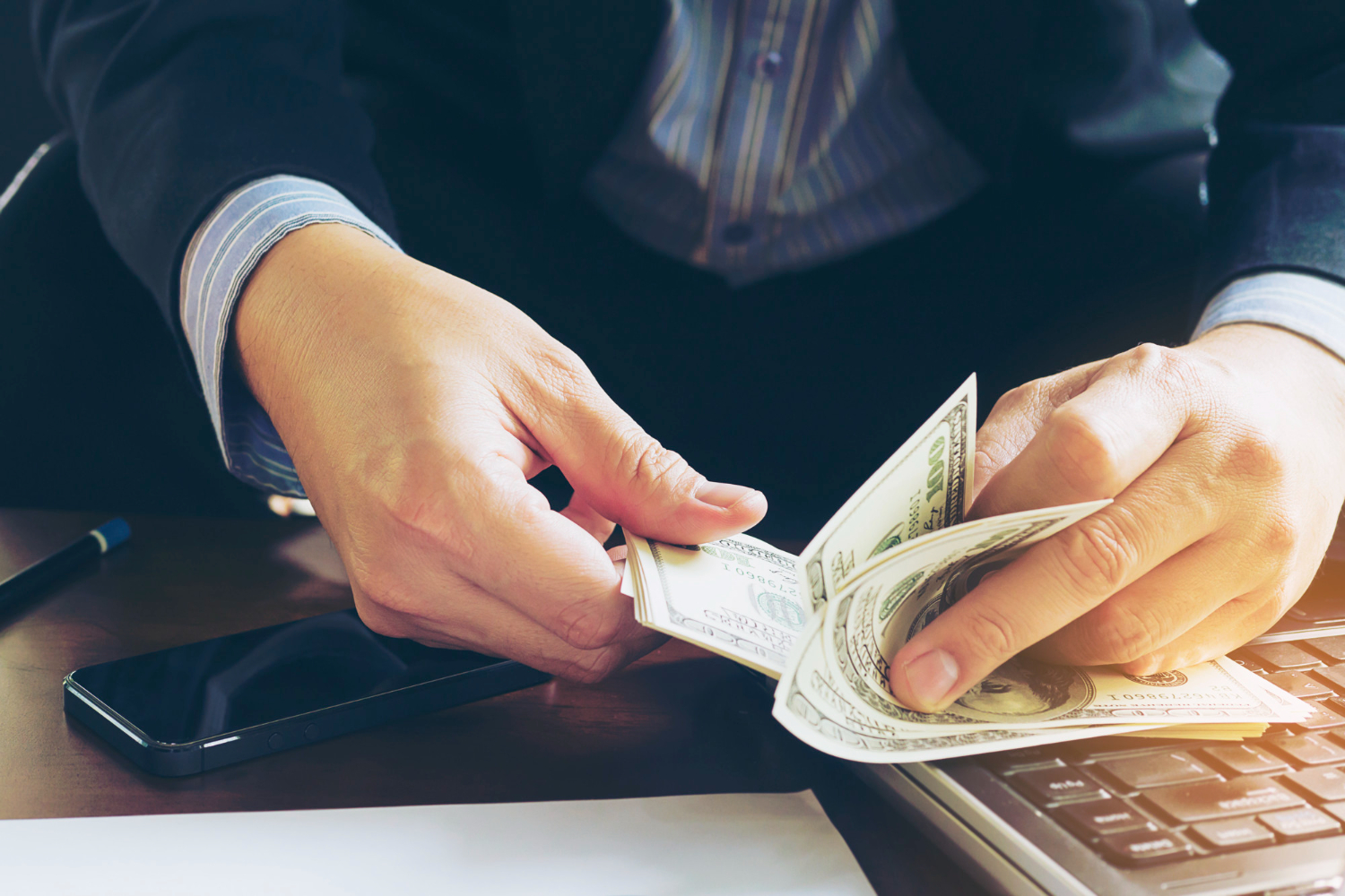 Businessman counting bank dollar notes in their office